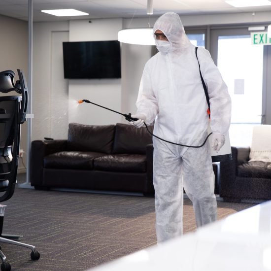 worker-wearing-protective-suit-face-mask-gloves-sanitizing-office-using-anti-bacterial-disinfectant-spray-hygiene-workplace-coronavirus-covid-19-pandemic-scaled.jpg
